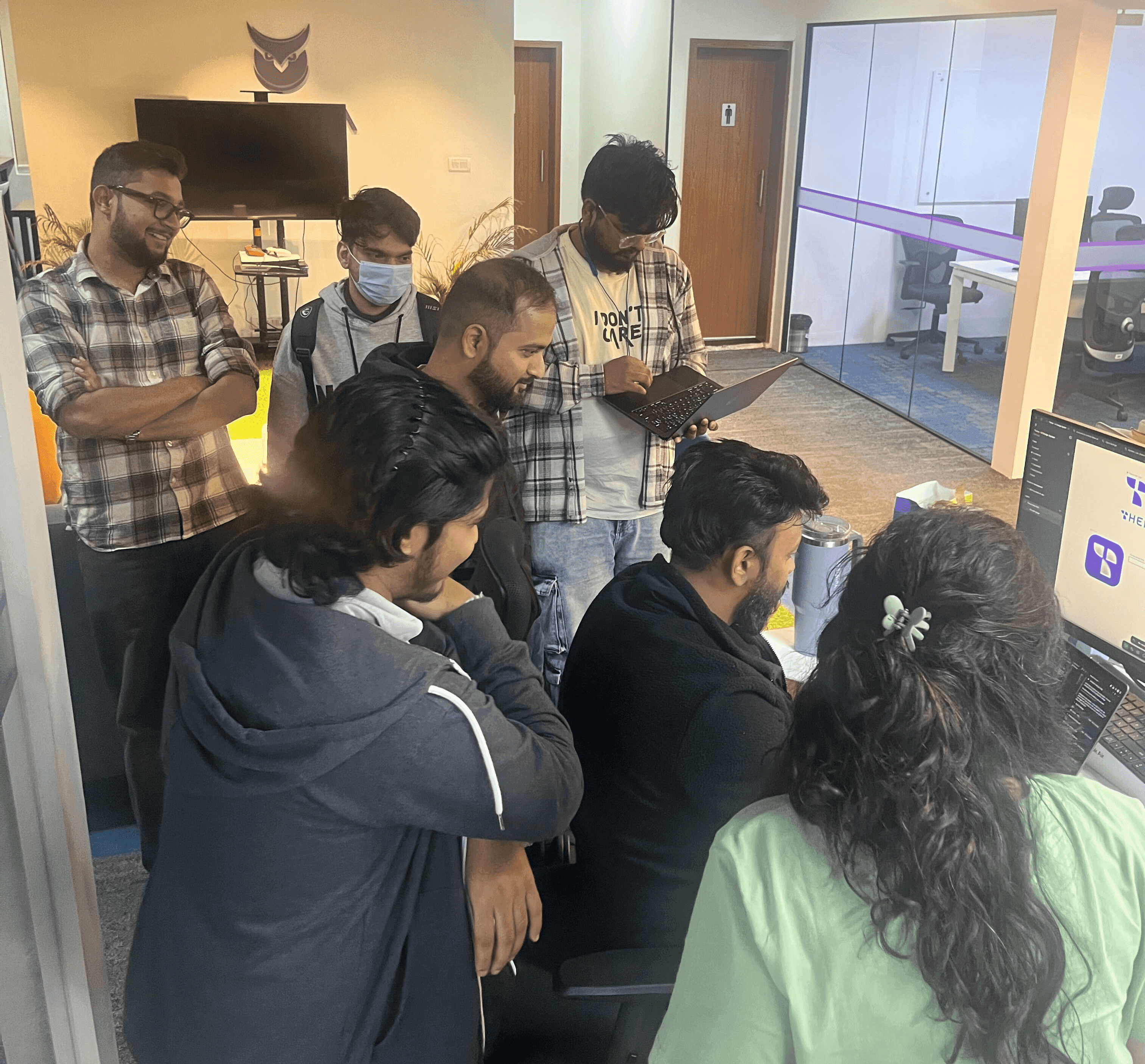 The Thena team gathered around a screen in the office